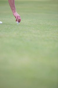 Hand placing ball on golf tee