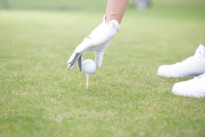 Cropped image of woman placing ball on golf tee