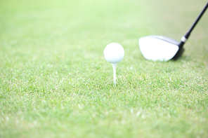 Close-up of golf club and tee with ball on grass