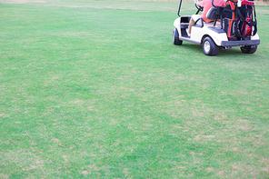 Low section of middle-aged man driving golf cart
