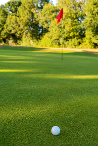 Golf ball, hole and red flag on the green of a golf course