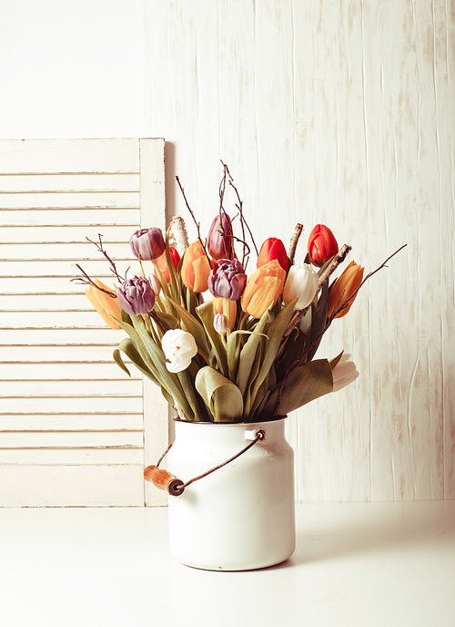Color tulips with branches in a white cane. Spring decor