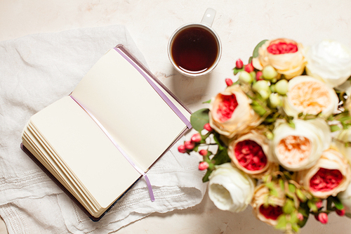 a cup of 홍차, notebook and beautiful flowers on the table, top view. the concept of inspiration to creativity