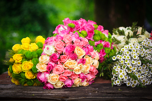 Two bouquets of pink and yellow roses on a wooden florist's table