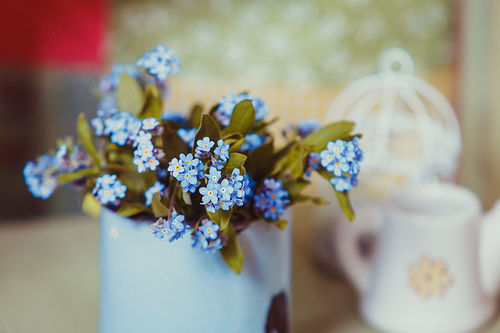 Bouquet of forget-me-not in a blue cup on a wooden windowsill