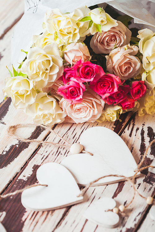 Luxury bouquet of roses lying on a wooden board and wooden hearts