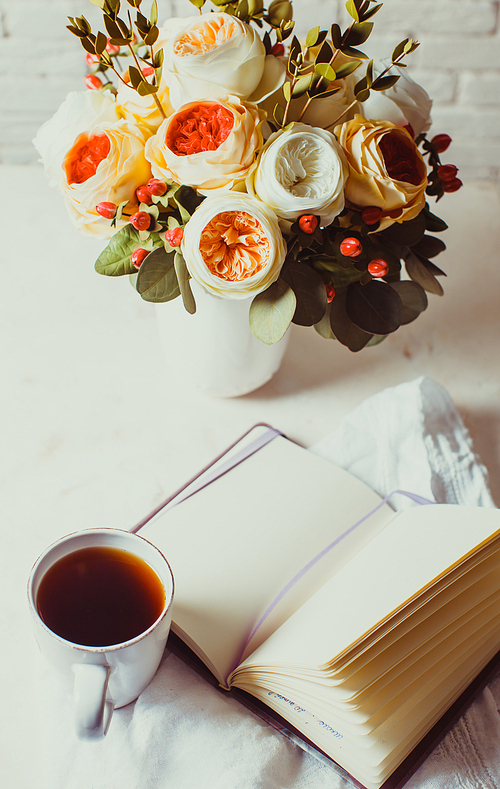 a cup of 홍차, notebook and beautiful flowers on the table. morning inspiration for the day planning