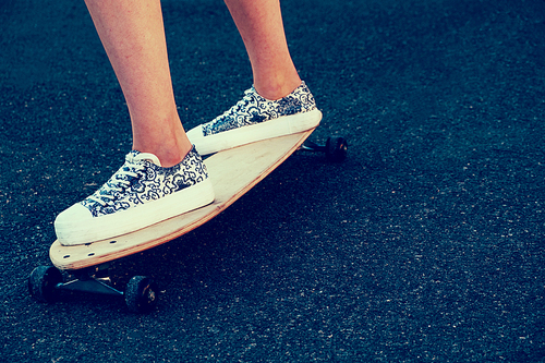 Side view of woman skateboarder legs with copyspace, skateboarding at sunrise city retro color