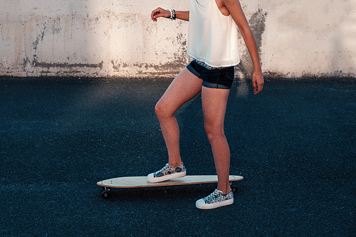 Girl on skateboard in scate park ready to push by her left leg and moving forward, side view shot with copyspace