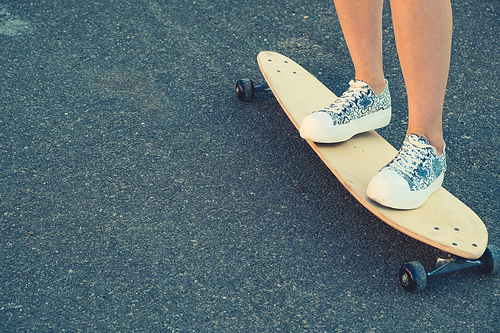 Young Girl legs standing on longboard closeup and a lot of copyspace