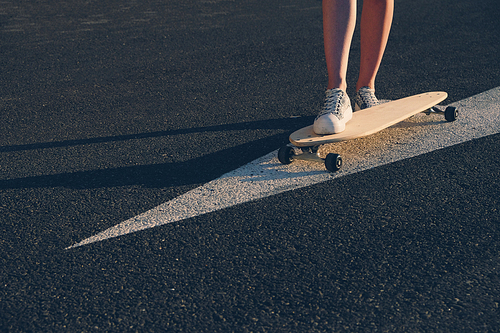 Skateboard on painted on asphalt arrow, legs on the board