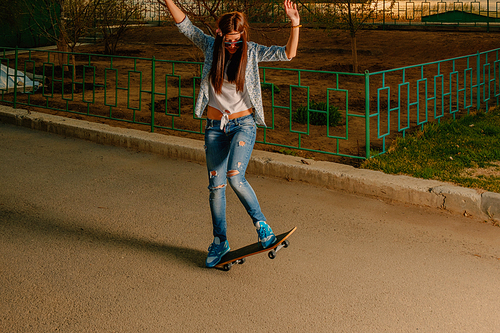 Hipster girl making trick on skateboard in the street
