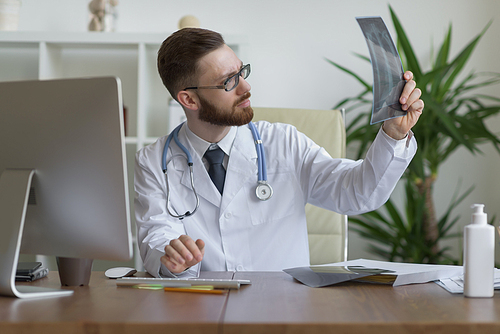 Thoughtful doctor holding chest and lungs xray in medical office