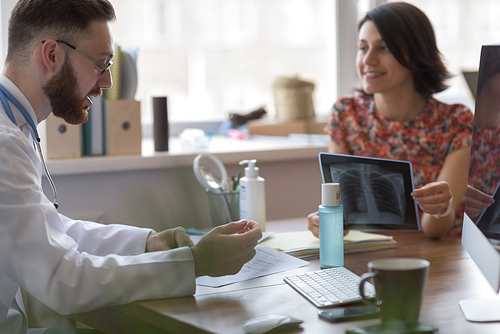 Confident practitioner consulting woman in hospital. Explaining results of chest x-ray scan