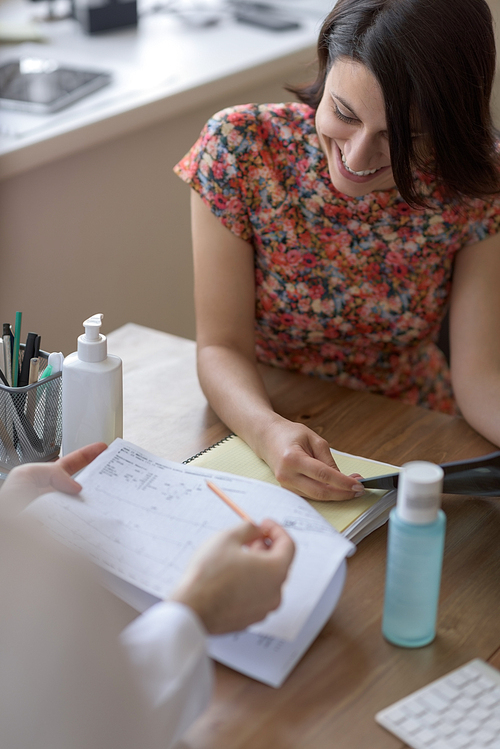 Confident practitioner consulting woman in hospital. Reading ecg results