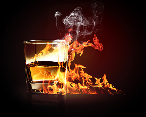 Image of glass of burning yellow absinthe