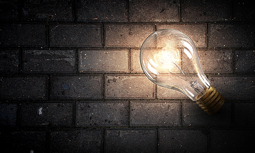 Power and energy concept with glass light bulb on brick wall
