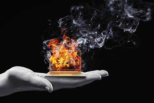 Human hand holding burning laptop on palm