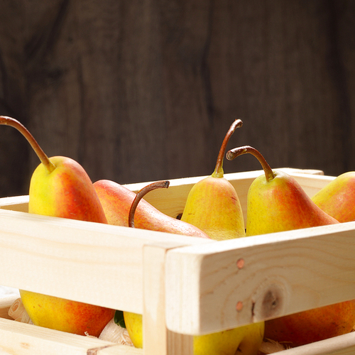 Wooden crate with organic pears on the white table