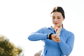 Young runner woman with heart rate monitor running on beach