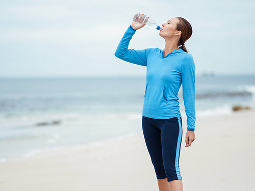 Sporty young woman drinking water on the sea coast
