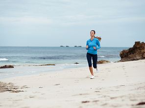 Sporty young woman running on the sea coast