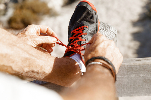 Male runner laces his shoes and prepares to jogging