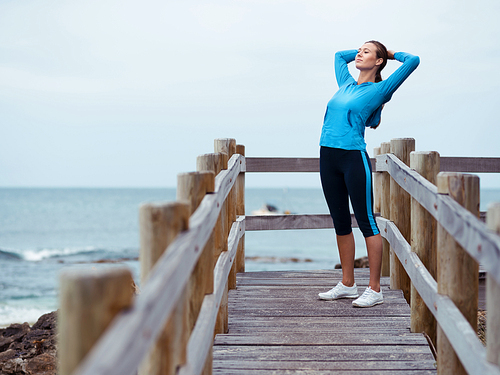 Sporty young woman stretching next to the sea coast