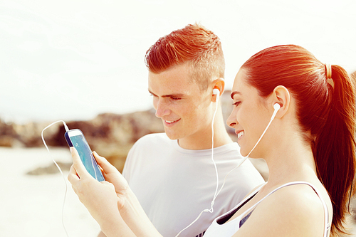 Young couple of runners with mobile smart phone  on beach