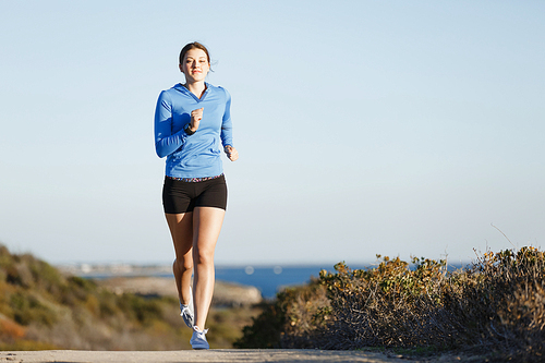 Fit female fitness model jogging along ocean