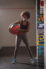 portrait of a young beautiful African American women carrying crossfit ball in gym