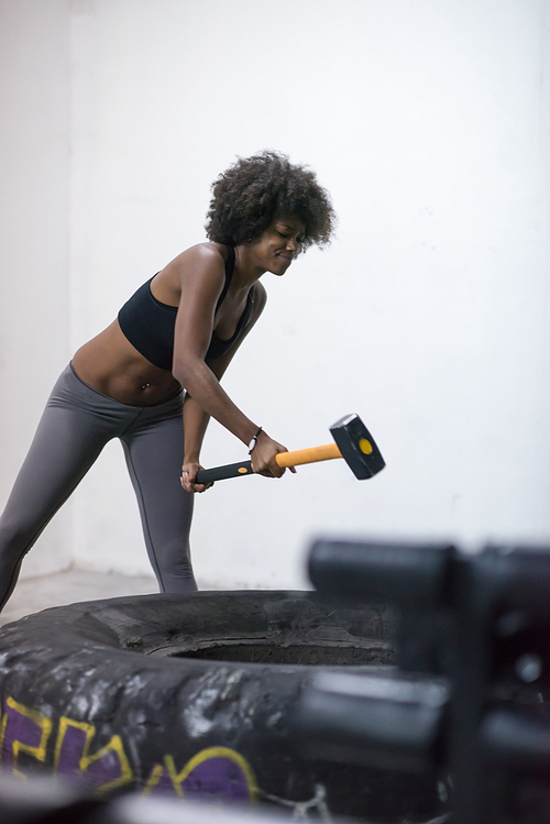 Sledgehammer Tire Hits african american woman workout at gym with hammer and tractor tire