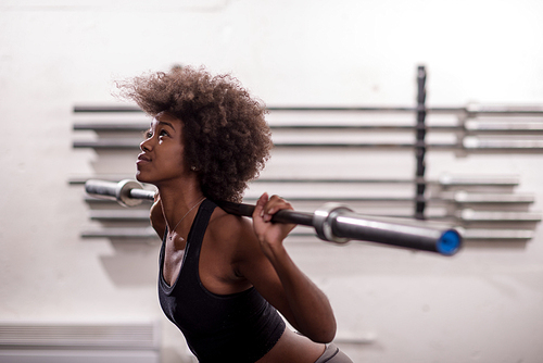 Young Cute african american sport woman in fitness room lifting empty bar