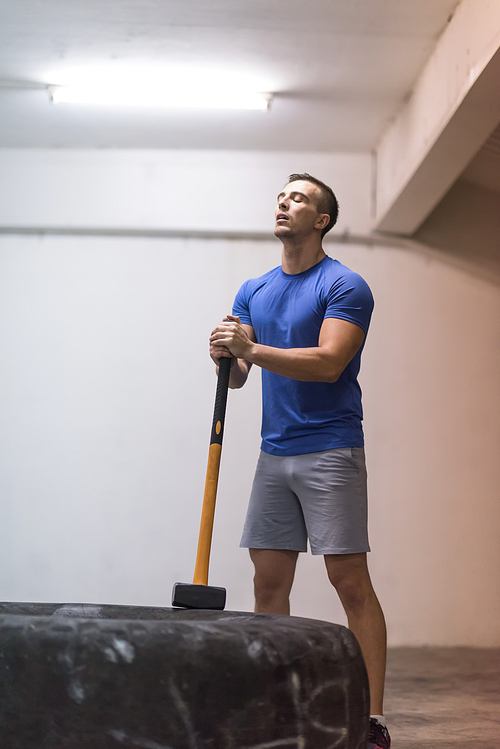 Sledgehammer Tire Hits young muscular man workout at gym with hammer and tractor tire