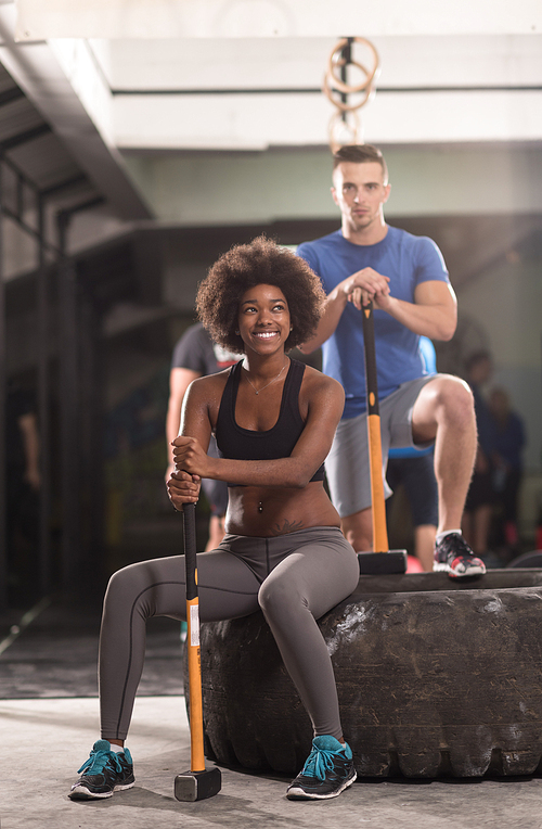 portrait of a young multiethnic couple after training with a sledgehammer and tractor tire