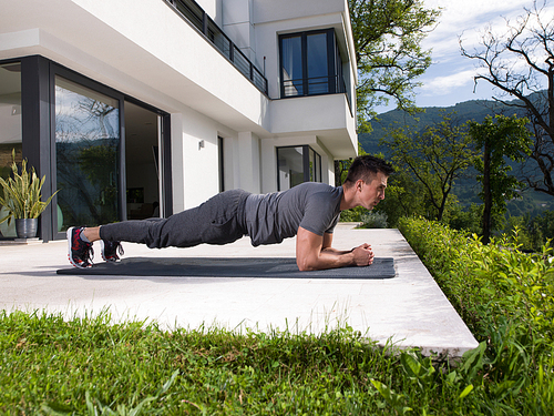 young handsome man doing morning yoga exercises in front of his luxury home villa