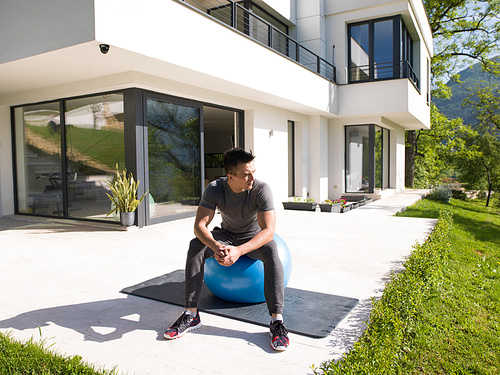 young handsome man doing morning yoga exercises in front of his luxury home villa