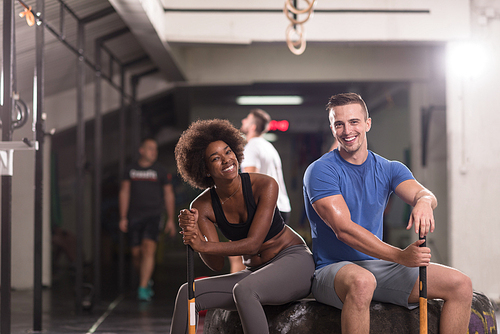 portrait of a young multiethnic couple after training with a sledgehammer and tractor tire