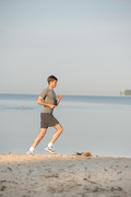 Man athlete/runner running on beach - jog workout well-being concept