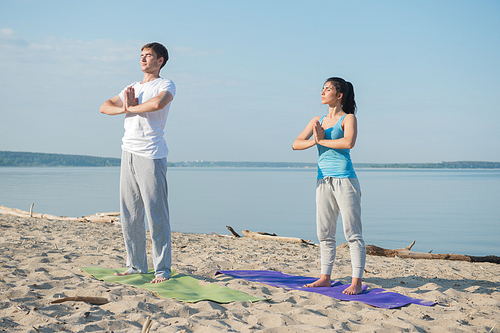 Morning Yoga Meditation at the Beach by young couple