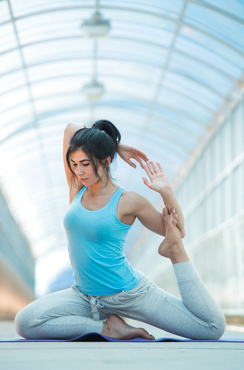 Woman doing stretching yoga exercises outdoors on the bridge. Full Length