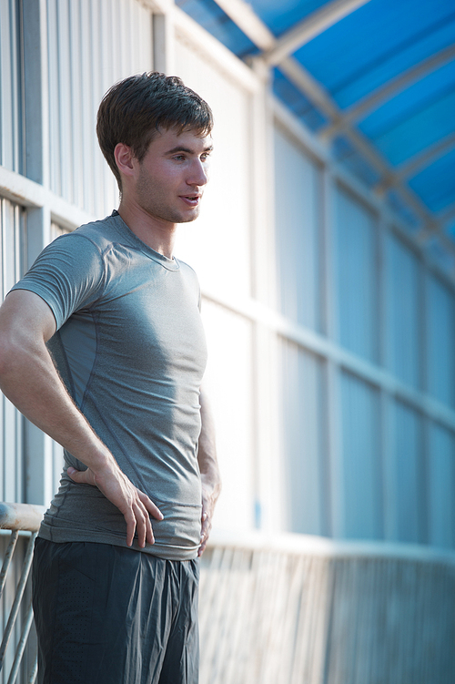 Jogger resting after running. Man runner taking a break during training outdoors in city. Young Caucasian male fitness model after work out.