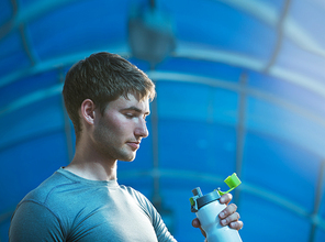 Young exhausted athlete drinking fresh water to refresh during a running trail