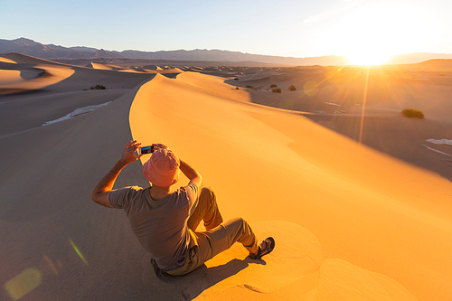 Hiker in sand desert. Sunrise time.