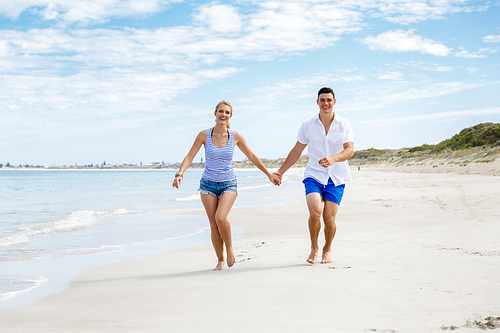 Romantic young couple on the beach walking along the shore