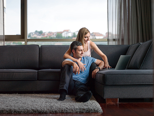 Attractive couple using a laptop in the living room