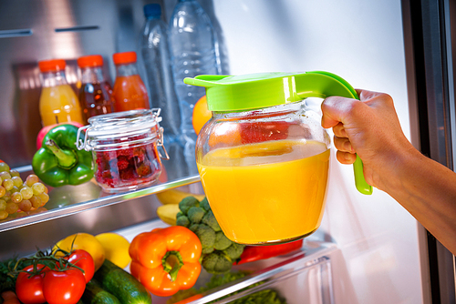 Woman takes the Orange juice from the open refrigerator