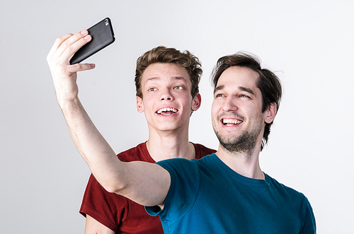 Two happy friends taking selfie on mobile phone camera