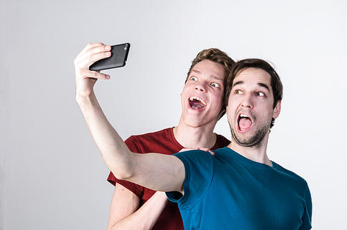 Two happy friends taking selfie on mobile phone camera