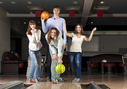 Group of four young smiling people playing bowling
